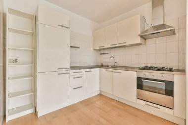 Geniş, boş bir stüdyo dairenin iç tasarımı. Geniş pencereleri, kaplaması ve mutfak setiyle döşenmiş beyaz duvarları var.