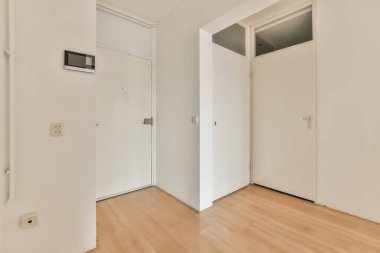 Beyaz duvarları ve parke zemininde parlayan lambasıyla aydınlık koridor.