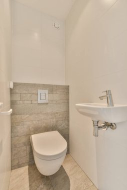 Lavabo ve ayna, tuvalet ve küvetin yanında beton duvara dayalı.