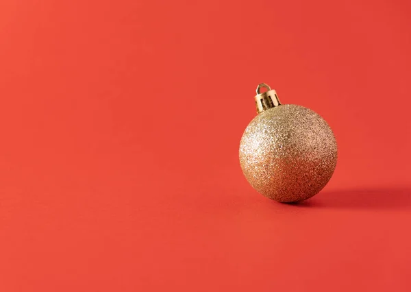 Gouden Kerstbal Een Rode Achtergrond Nieuwjaarsconcept — Stockfoto