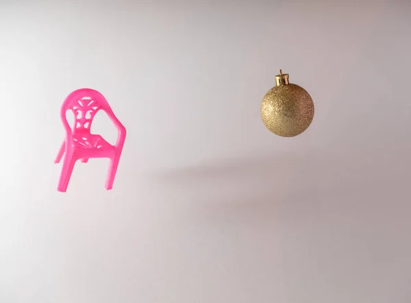 Altın rengi Noel balosu olan pembe sandalye. Minimum Yeni Yıl konsepti..
