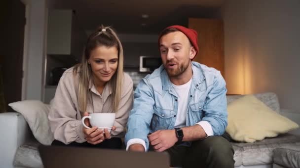 Szczęśliwy kaukaski para pracuje z domu siedzi na kanapie śmiejąc się podczas pisania na laptopie — Wideo stockowe
