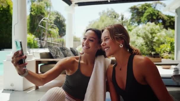 Sekarotuiset naispuoliset ystävät ottavat selfietä aktiivisen harjoittelun jälkeen kotona eristämällä lukituksen aikana — kuvapankkivideo