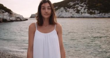 Güzel beyaz kadın okyanusun kenarında dikiliyor. Kocasının gözlerinin içine bakıyor.