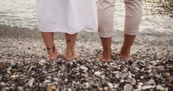 Feliz pareja caucásica en vacaciones románticas caminando en la playa de pie en el agua — Vídeo de stock