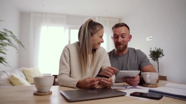 Kaukasisches Paar sitzt zu Hause und kauft online Möbel für sein neues Zuhause — Stockvideo