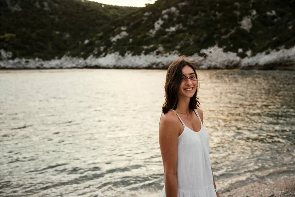 Güzel beyaz kadın okyanusun kıyısında gülümsüyor ve balayının tadını çıkarıyor.