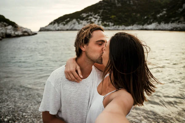 Gelukkig Kaukasisch paar zoenen terwijl het nemen van selfie op het strand — Stockfoto