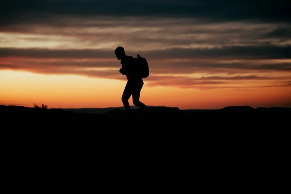 Beyaz erkek maceracı gün batımında dağda yürüyüş yaparken sırt çantası takıyor. — Stok fotoğraf