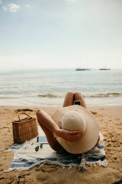 Caucasian girl tanning on beach wearing straw sunhat Royalty Free Stock Photos