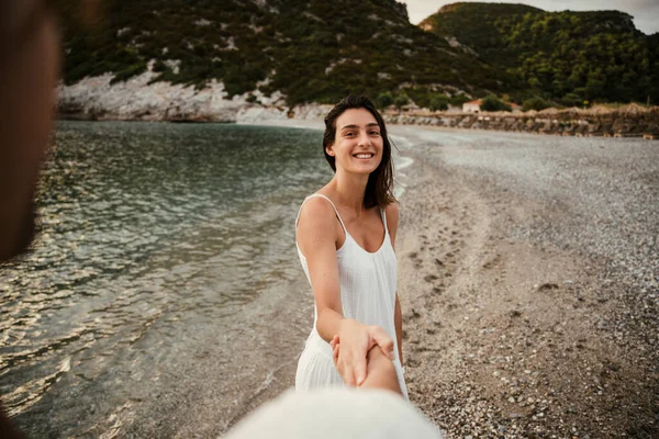 Blank vrouw vasthouden handen met vriendje lopen op het strand — Stockfoto