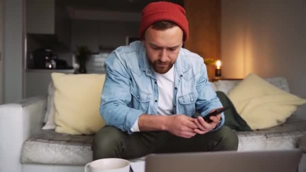 Vit man som arbetar hemifrån får en rolig text på cellulära enheten — Stockvideo