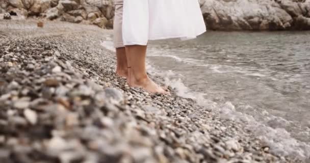 Gelukkig paar staan in het zand door de oceaan het dragen van wit stroom kleding — Stockvideo