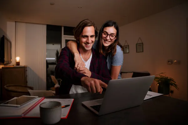 在家里打字的白种人快乐的夫妻，手挽手在笔记本电脑上打字 — 图库照片