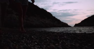 Güneş battıktan sonra kumsalda yürüyen beyaz bir çift.