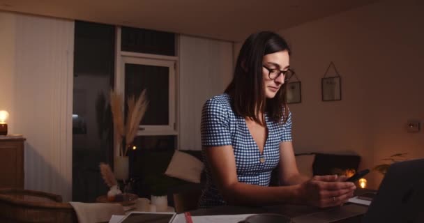 Белая женщина работает допоздна, печатает на ноутбуке — стоковое видео