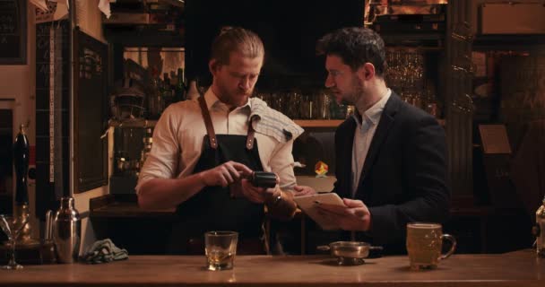 Caucasian male manager teaching bartender how to use card machine — Stockvideo