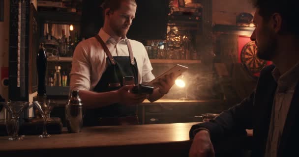 Camarero masculino caucásico de pie sosteniendo tableta digital mientras suena la factura para el cliente — Vídeos de Stock