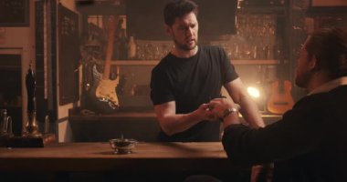 Caucasian male serving customer behind bar