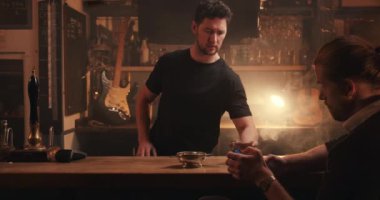 İngiliz barında sofistike bir adama beyaz erkek barmen içki dolduruyor.