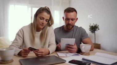 Kafkasyalı çift mutfak masasında dijital tablet kullanarak online alışveriş yapıyor.