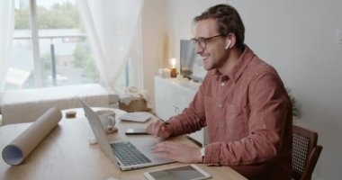 Beyaz erkek öğrenci evde çalışıyor. Bilgisayarda daktilo yazıyor.