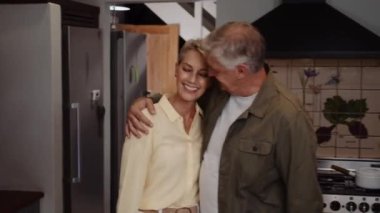 Beyaz, olgun bir çift mutfakta sevgi gösteriyor. 