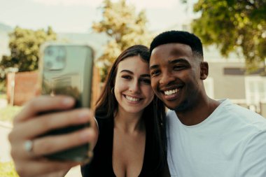 Parkta selfie çekerken gülümseyen çift.