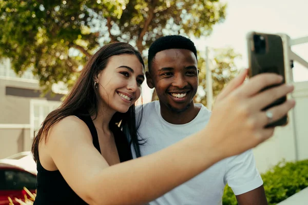 Pareja Biracial tomando selfies por teléfono en la universidad — Foto de Stock