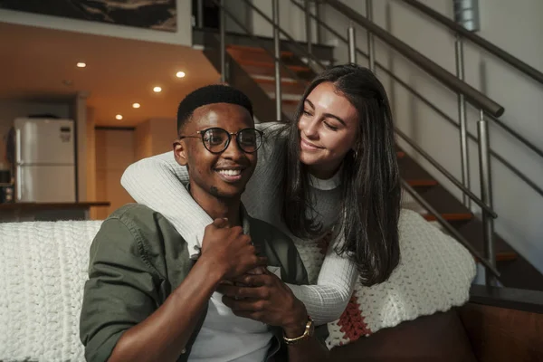 Afro-Amerikaanse man en Kaukasische vriendin tonen genegenheid op de bank terwijl knuffelen elkaar — Stockfoto
