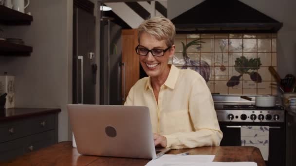 Зріла біла жінка працює з дому на кухні — стокове відео