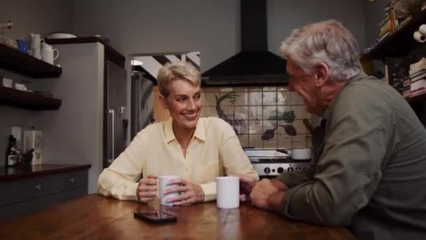 Romantický starší pár sedí v kuchyni pití kávy hraní roztomilé