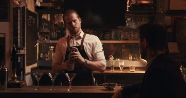Beyaz erkek barmen barın arkasında kokteyl hazırlıyor.