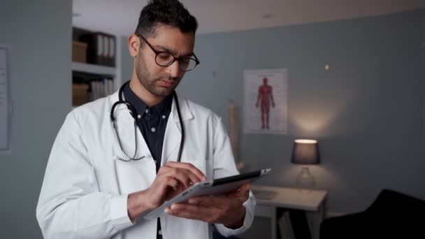 Médico masculino de raza mixta escribiendo en tableta digital — Vídeos de Stock