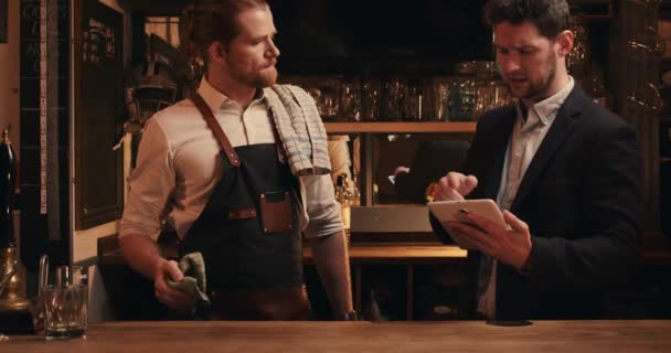 Vit manlig bartender stående med manager håller digital tablett — Stockvideo