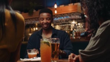 Restoranda cep telefonu ve kart makinesiyle yemek için para ödeyen Afro-Amerikalı bir erkek.