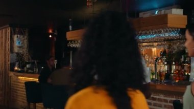 Afro-Amerikalı garson kadın müşterileri kapıda karşılıyor.