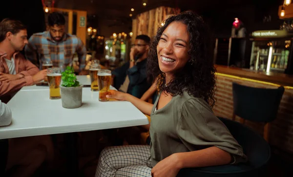 Mujer afroamericana riendo mientras disfruta de bebidas con amigos — Foto de Stock