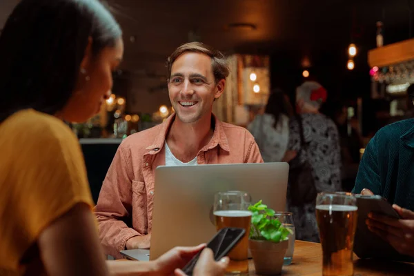 Diversos colegas para las bebidas que trabajan en el restaurante usando el ordenador portátil — Foto de Stock