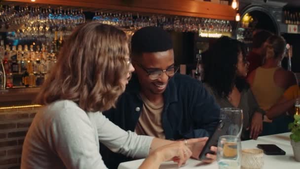 Разнообразная группа друзей за ужином смеются над сотовым устройством — стоковое видео