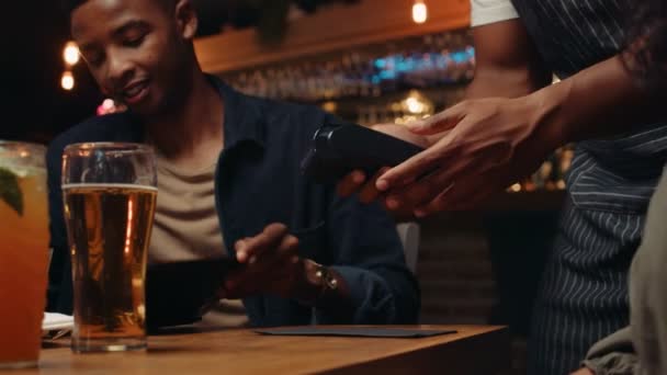 Dispositivo cellulare di intercettazione maschile afroamericano sulla macchina della carta che paga per la cena — Video Stock