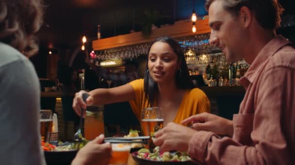 Разнообразная группа друзей, обедающих в ресторане, дегустируя еду — стоковое видео