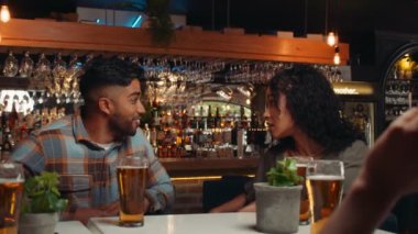 Diverse group of friends out for dinner laughing while having drinks