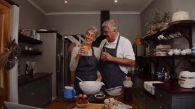 Romantik Kafkasyalı yaşlı çift yemek pişirirken portakal suyu içiyor. 