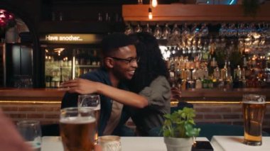 African American friends hugging while out for dinner with group