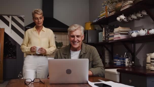 一对快乐的高加索夫妇坐在厨房里通过视频通话 — 图库视频影像