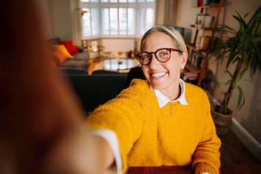 Caucasian female woman working from home taking selfie in living room