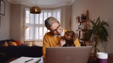Caucasian female working from home holing pet dog