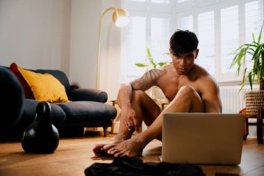 Asian male exercising virtually on laptop