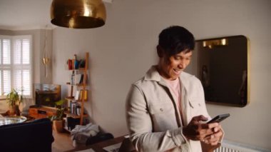 Genç Asyalı adam cep telefonunda geziniyor.